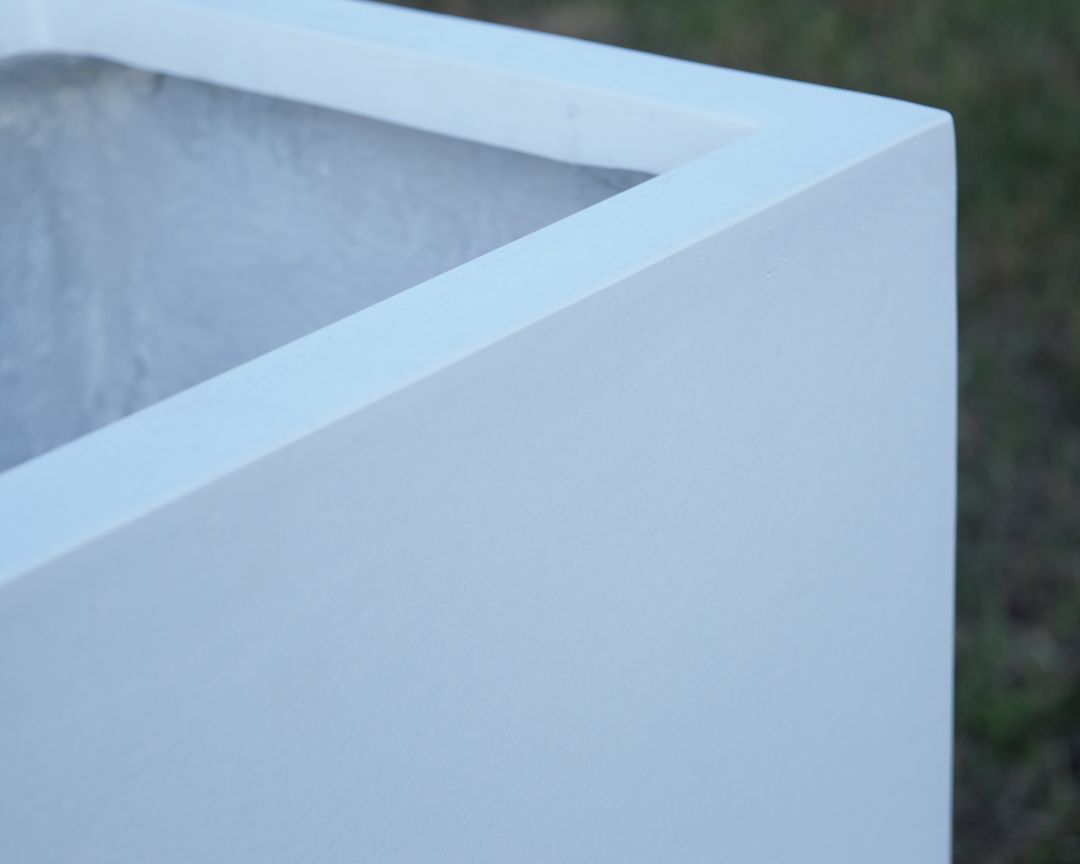 Nahaufnahme der oberen Ecke eines rechteckigen Pflanzkübels aus Fiberglas in Perlmuttweiß mit glatter Oberfläche und Rand
