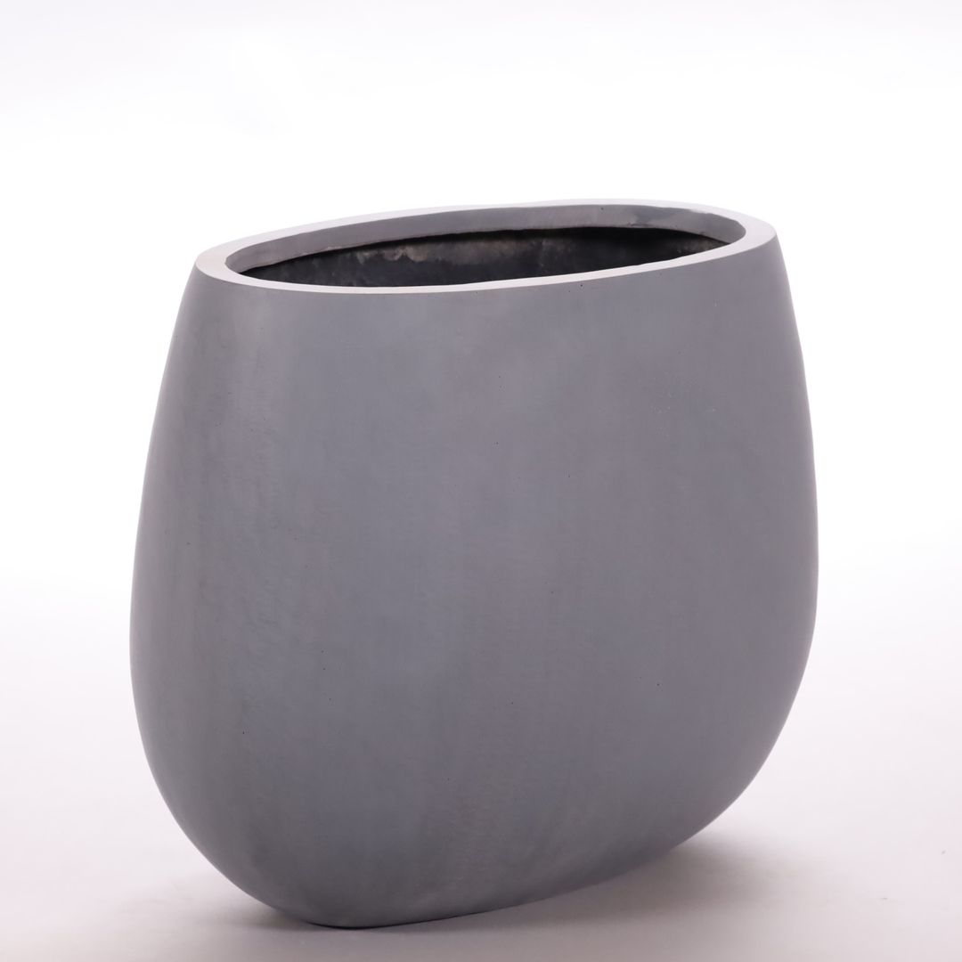 Ovaler Pflanzkübel aus Fiberglas in Grau mit flacher, bauchig abgerundeter Form vor hellem Hintergrund