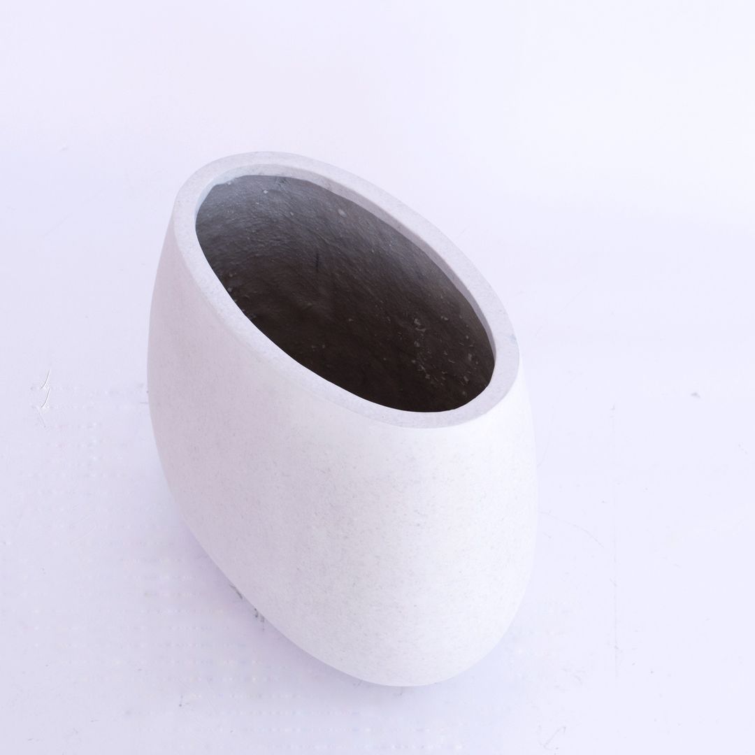 Ovaler Pflanzkübel aus Fiberglas in Perlmuttweiß, schräg von oben fotografiert mit Blick in den dunklen Innenraum