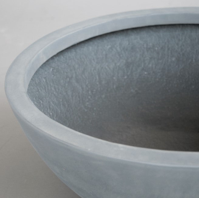 Nahaufnahme einer runden grauen Pflanzschale aus Fiberglas mit glattem Rand und strukturierter Innenseite