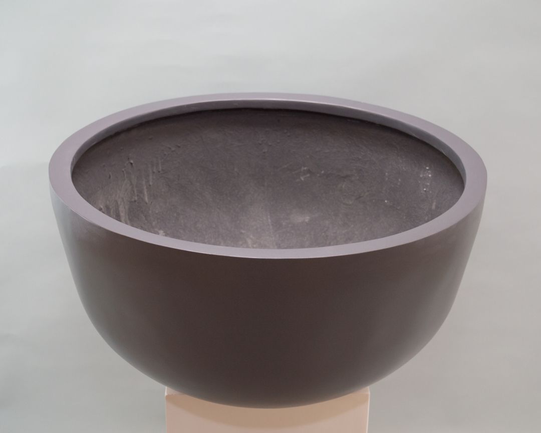 Runde Pflanzschale aus Fiberglas in Anthrazit metallic auf einem hellen Sockel mit Blick in den Innenraum