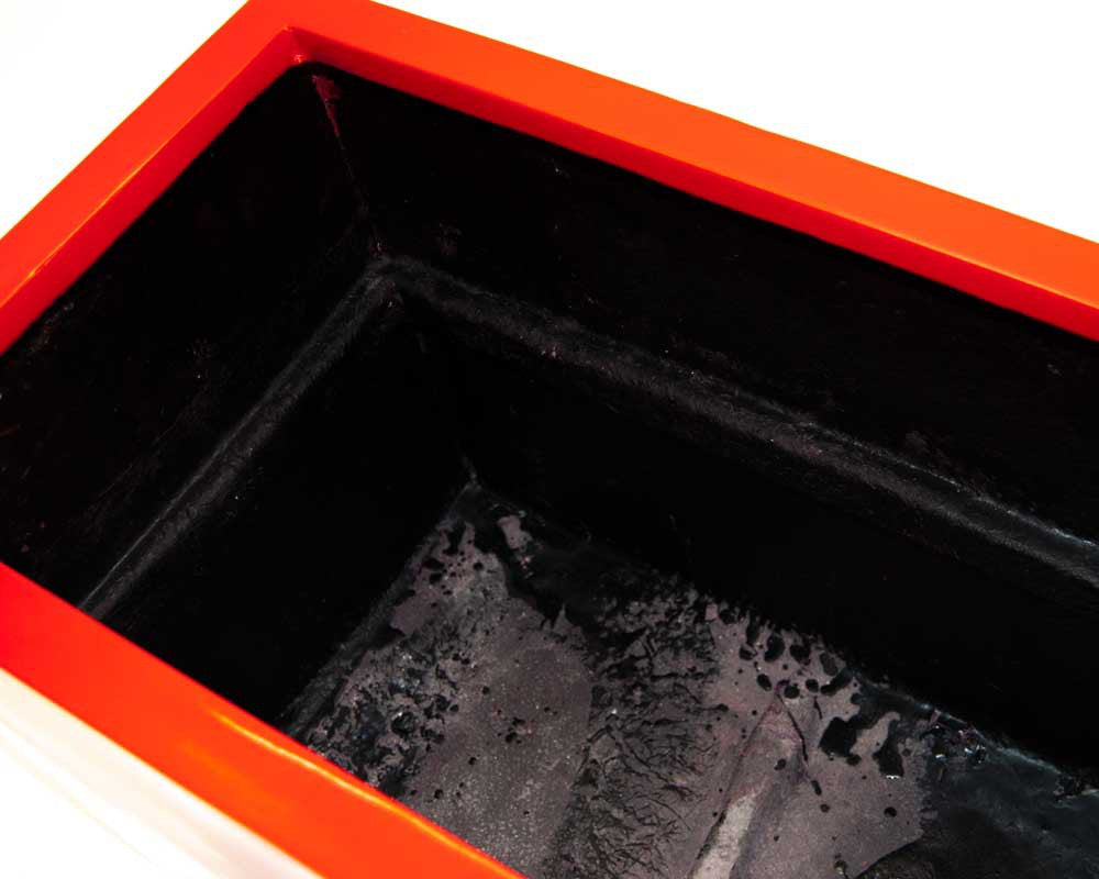 Detailansicht in einen rechteckigen Pflanzkübel mit glänzend rotem Rand und schwarzer Innenseite