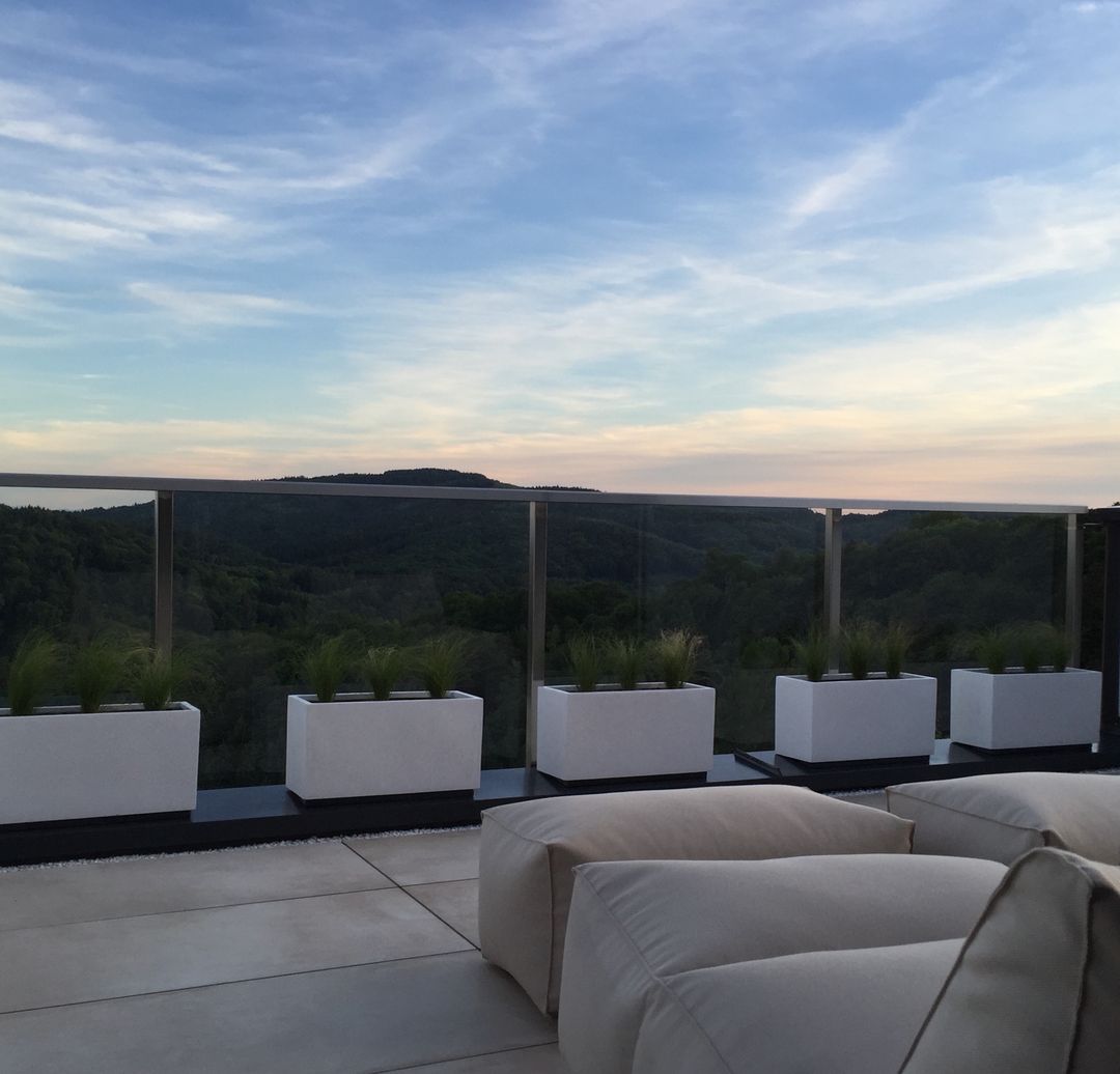 Pflanzkübel Fiberglas rechteckig 100x40x50cm perlmutt weiß in Fünferreihe mit Ziergras an einem Glasgeländer mit Panoramablick